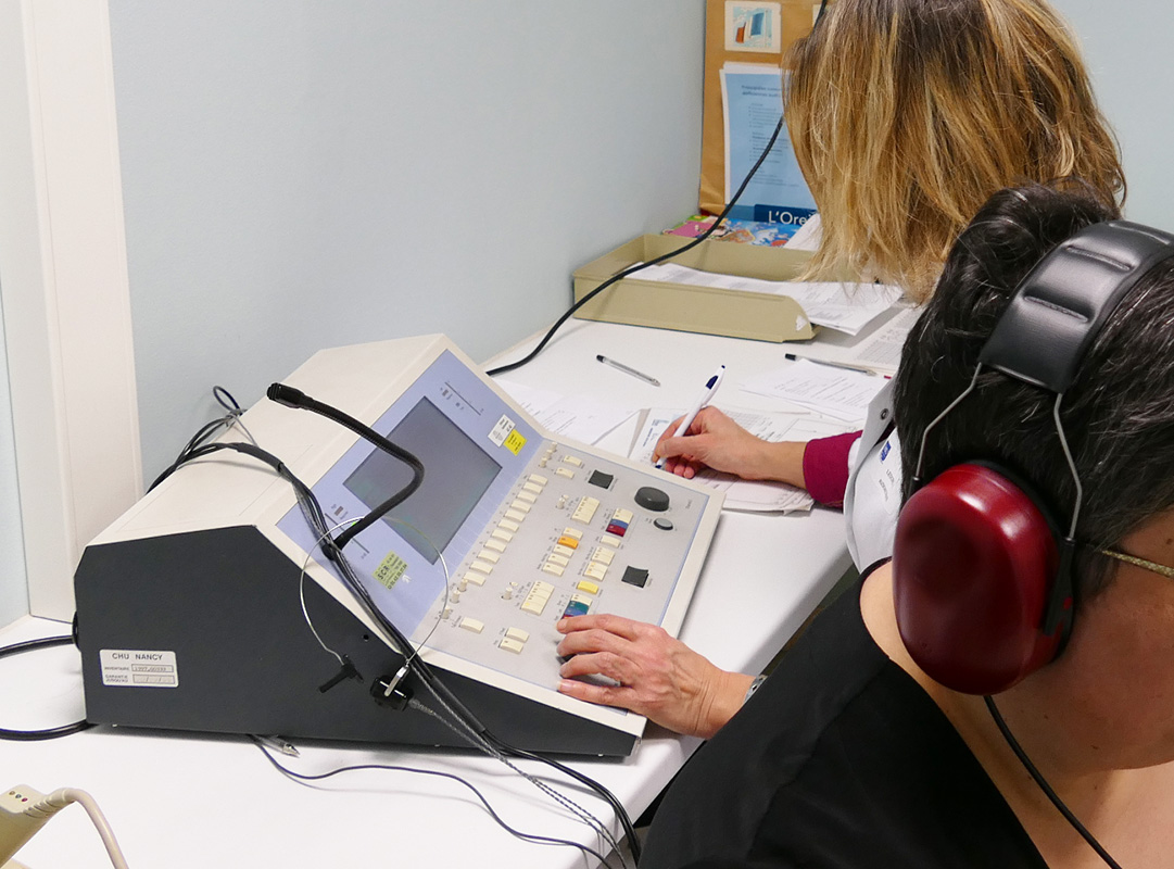 Réalisation d'un test d'audition : la patiente a un casque audio et l'audiométriste note les résultats.