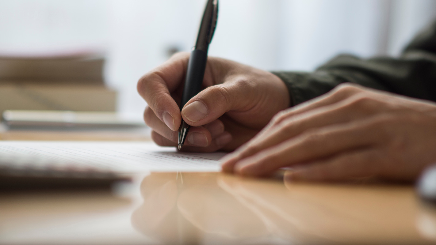 Photo d'un plan serré sur une personne écrivant sur un papier