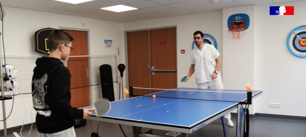 Photographie d'une séance de ping pong entre l'adolescent hospitalisé et l'éducateur spécialisé