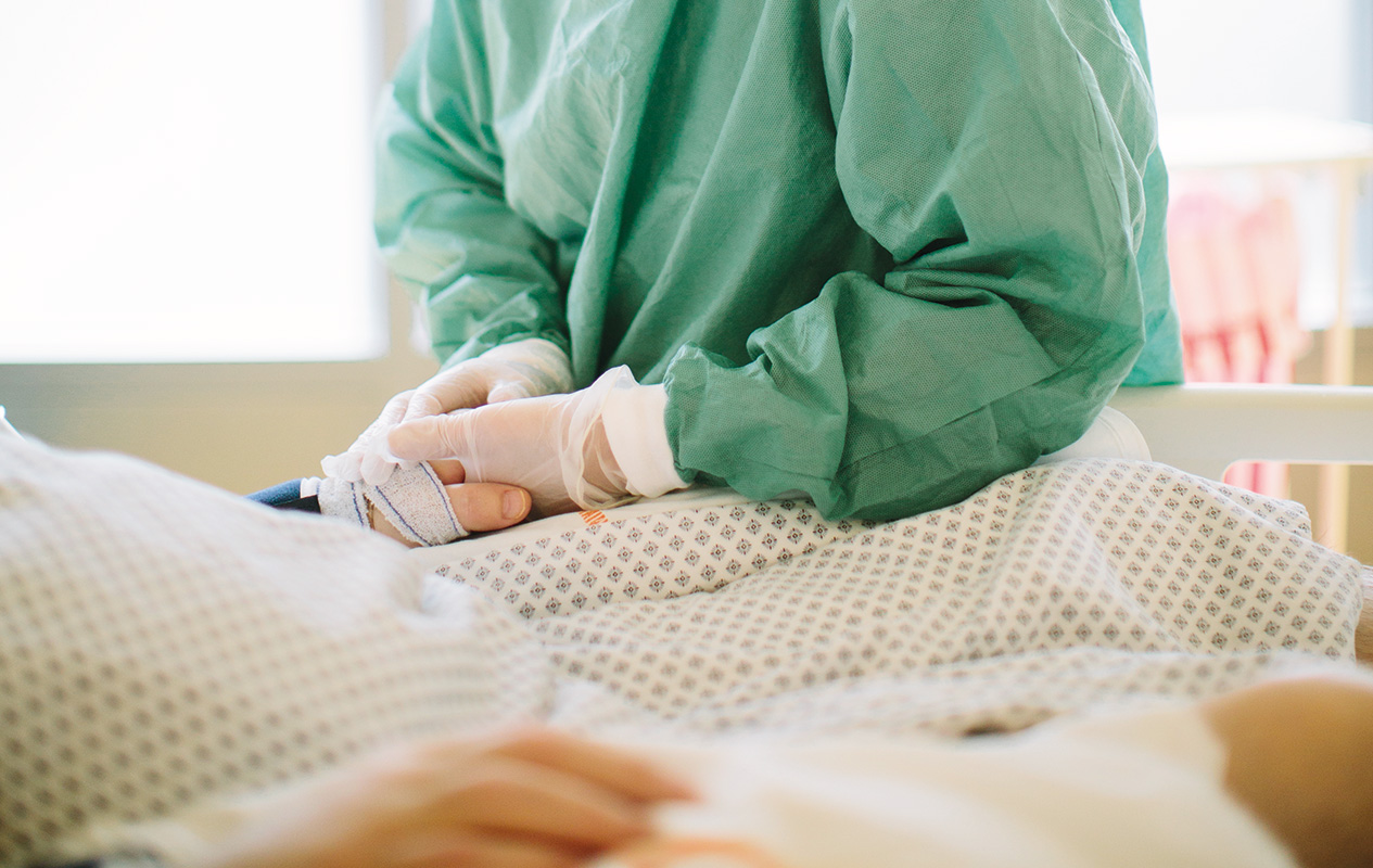 Photo d'un soignant tenant la main d'un patient alité