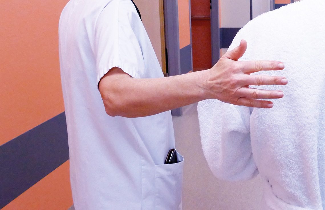 Photo d'une soignante accompagnant un patient dans un couloir