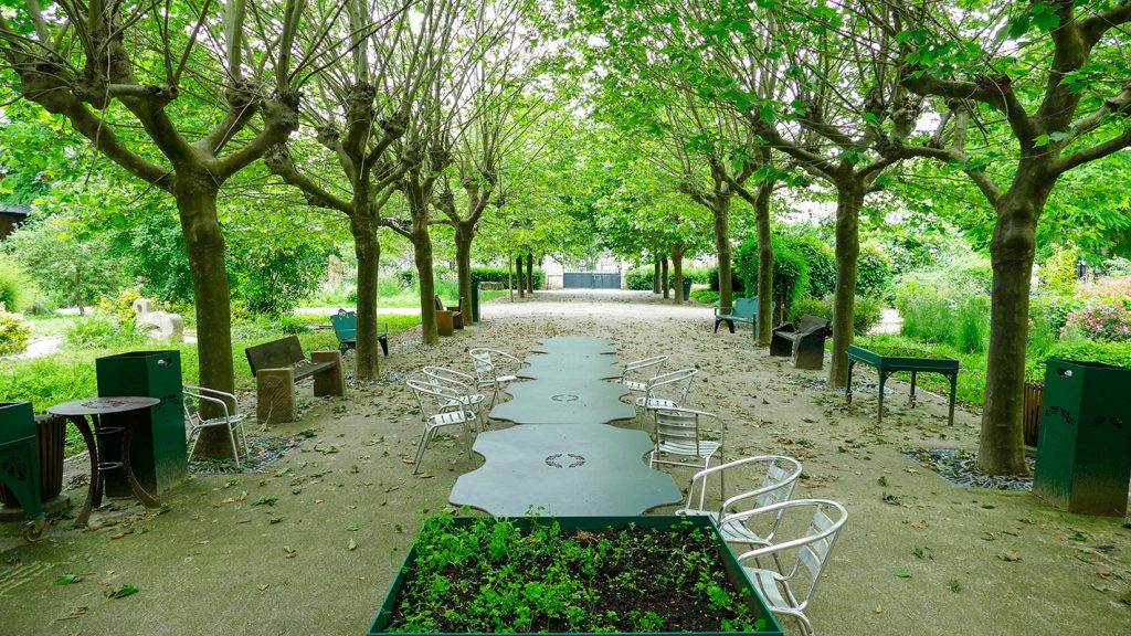 Vue sur l'allée centrale du jardin et son mobilier pour accueillir les patients et leurs visiteurs