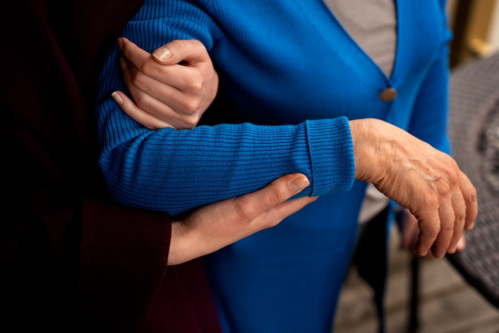une personne aide une personne plus âgée à marcher