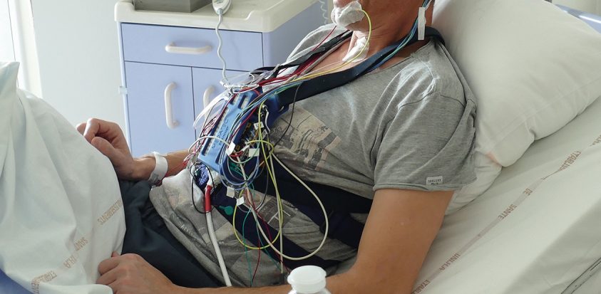 Photo d'un patient équipé du dispositif de polysomnographie et installé dans sa chambre d'hospitalisation