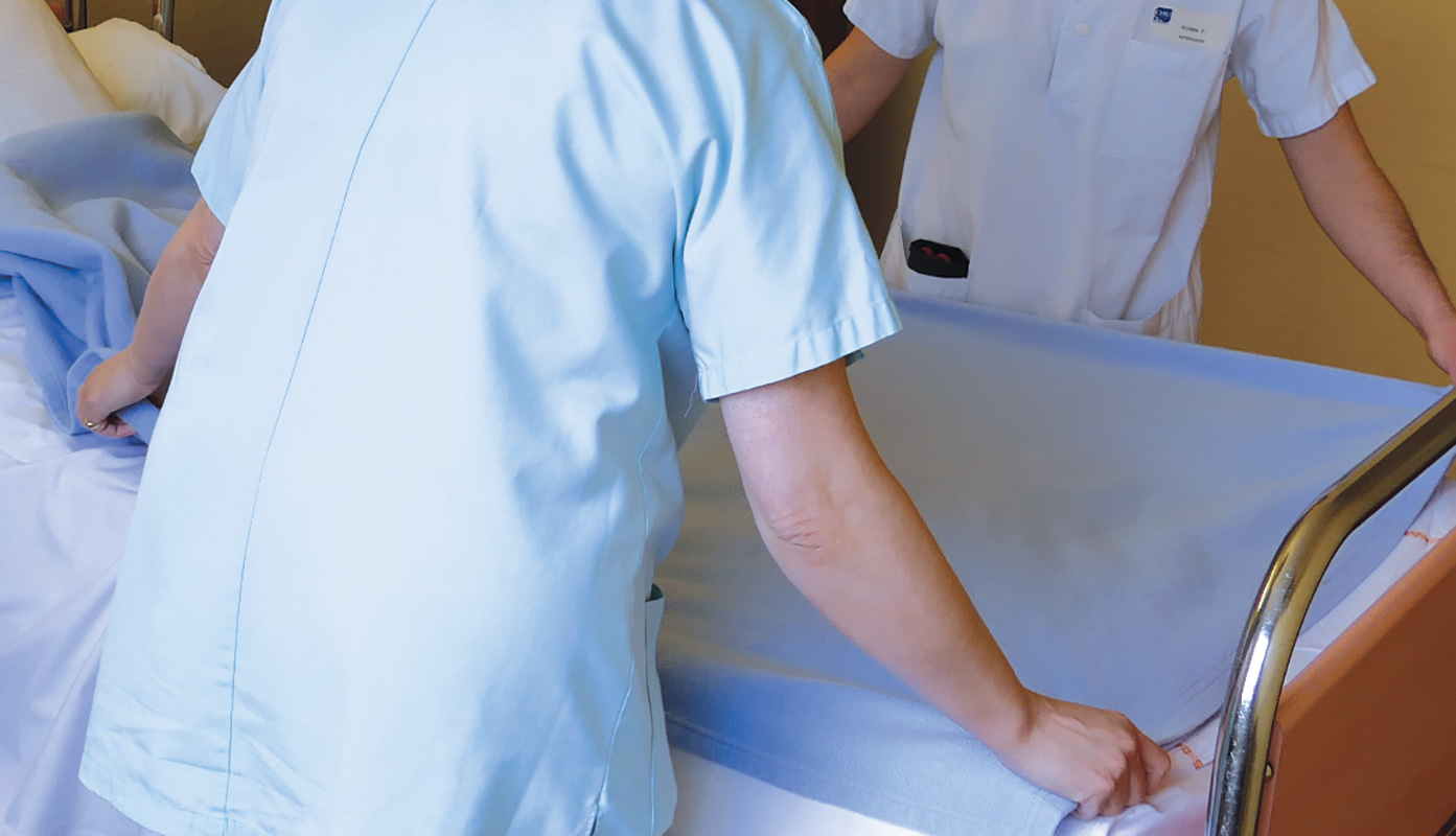 deux soignantes préparent un lit dans une chambre d'hopital